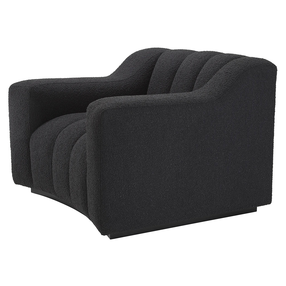 Fekete színű buklé szövettel kárpitozott dizájn fotel.