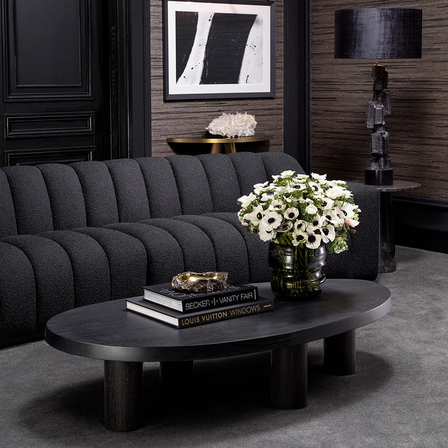 Art Deco ihletésű, modern kortárs stílusú, íves kialakítású fekete színű buklé szövettel kárpitozott óriás dizájn kanapé.