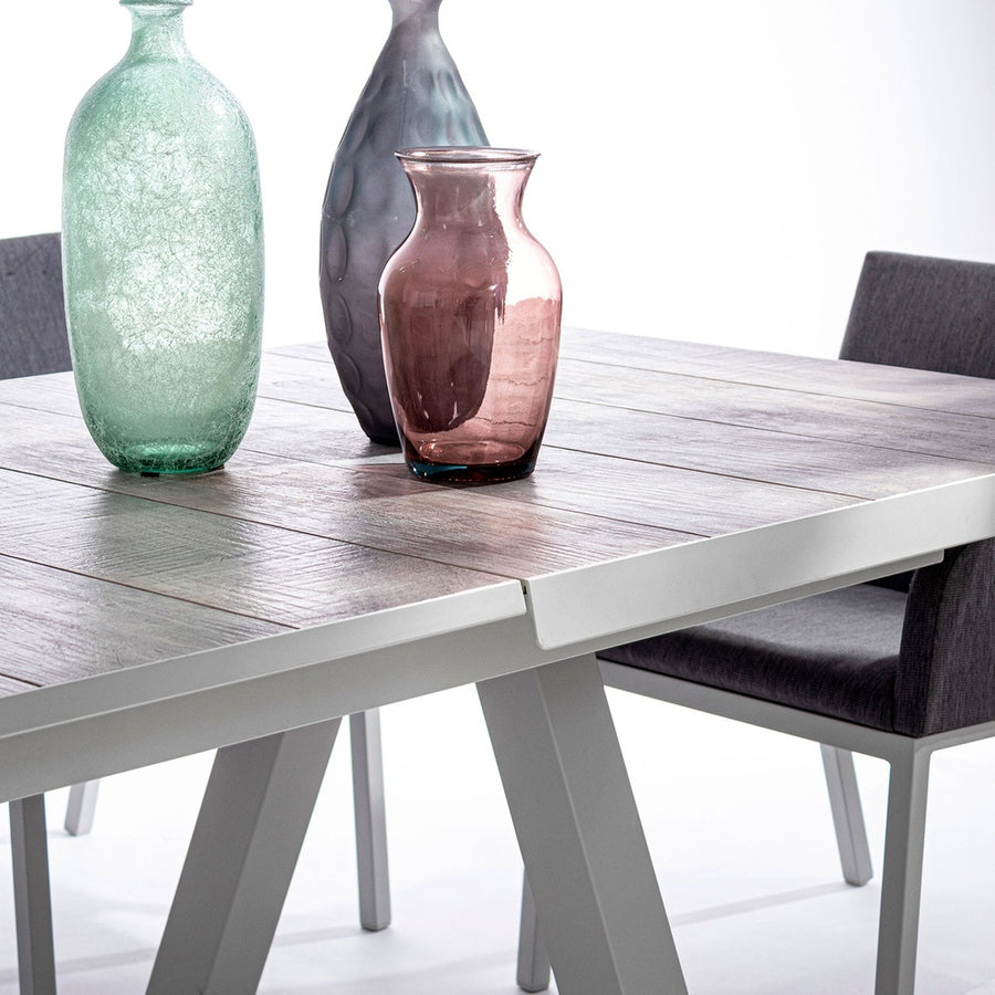 Krém színű kortárs kerti étkezőasztal. színes üveg vázákkal.