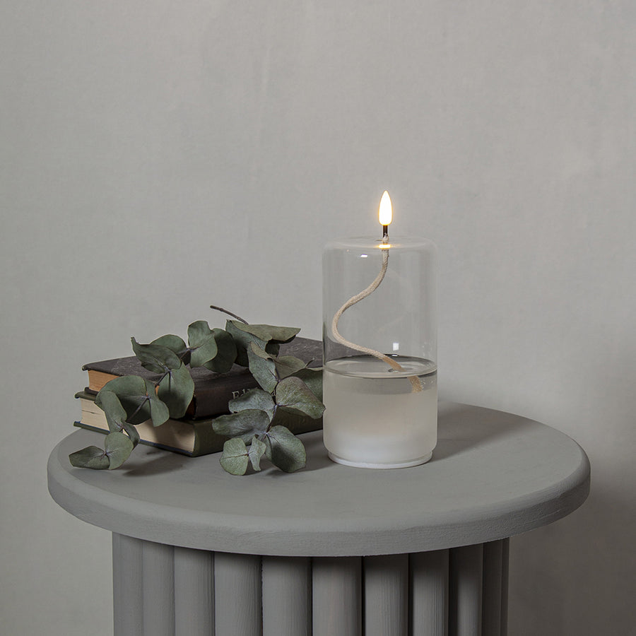 Áttetsző henger formájú, üvegből készült, textilkanócos LED olajlámpa.