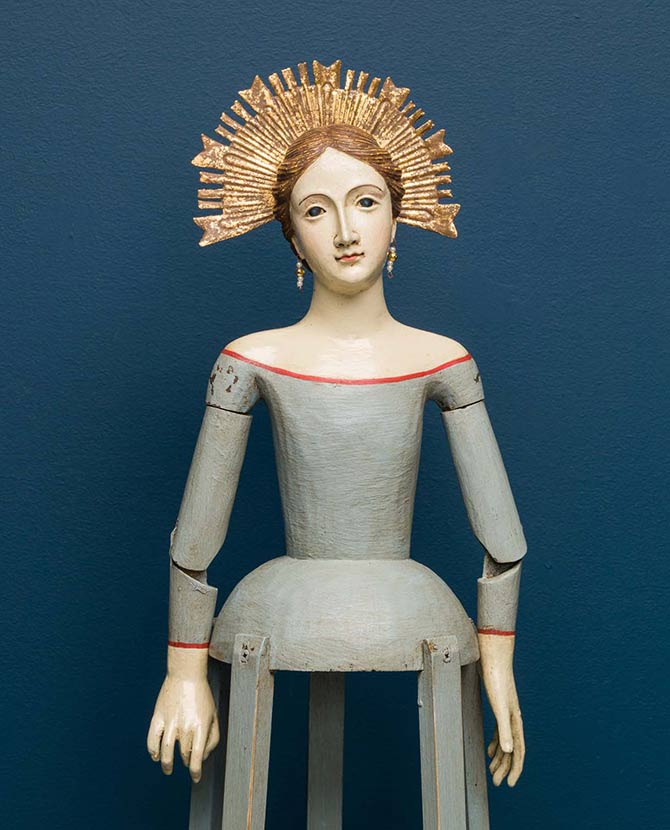 Mozgatható, pozícionálható karokkal kialakított gyertyatartós Madonna figura.
