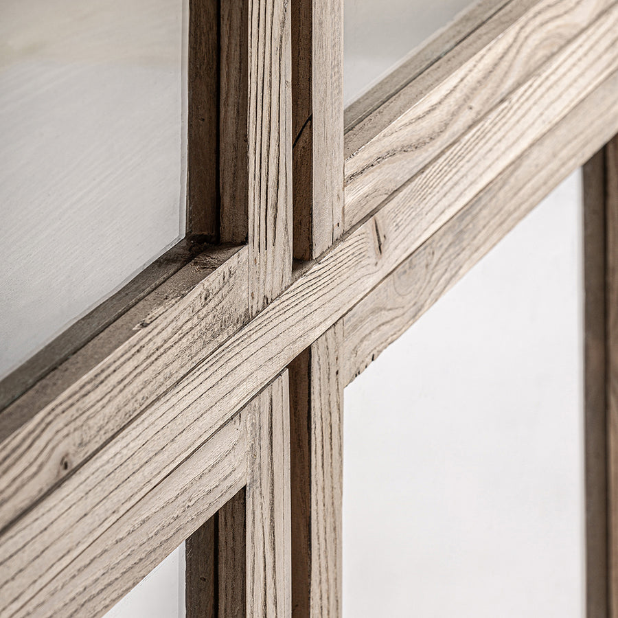 Közelkép a vitrinszekrény kereszteződő fa kereteiről és üvegfelületéről.