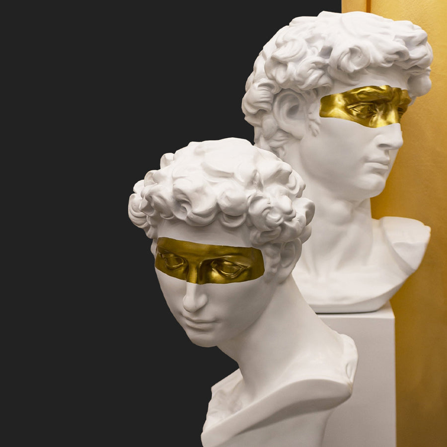 Aranyszínű maszkkal kontrasztozott, nagy méretű, fehér színű férfi mellszobor..