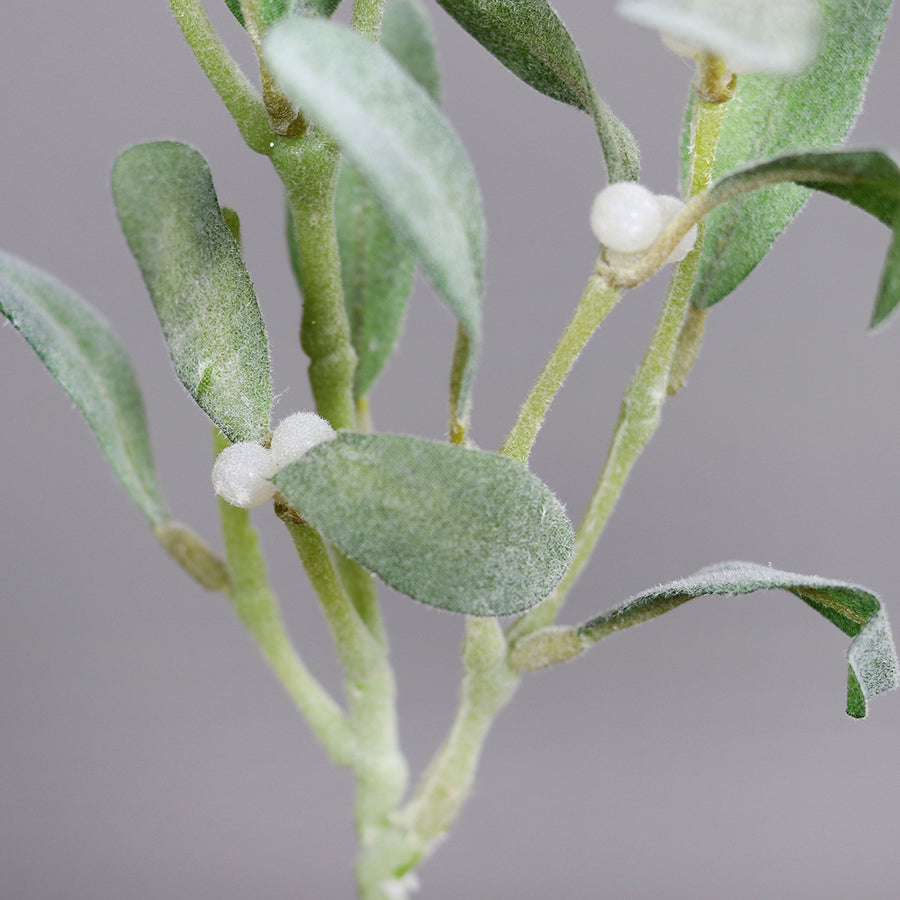 Karácsonyi dekorációhoz készült mű fagyöngy ág fehér bogyókkal és élethű zöld levelekkel.