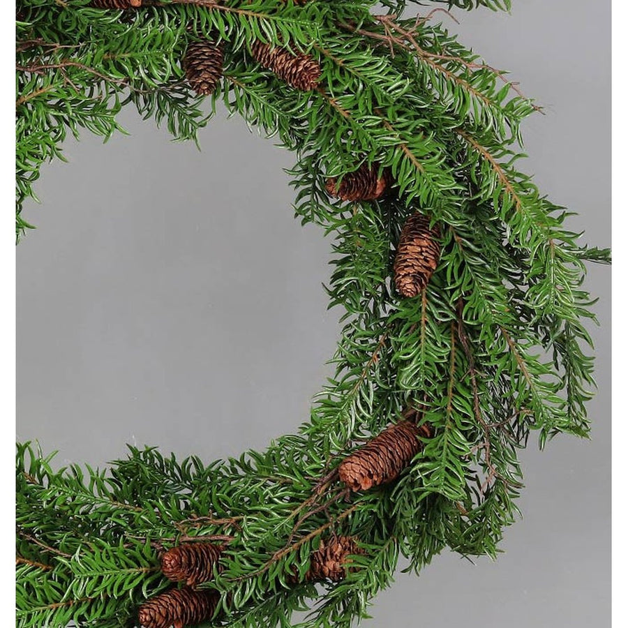 Mesterséges nobilis fenyőágakból készült, tobozokkal díszített ajtódísz koszorú.