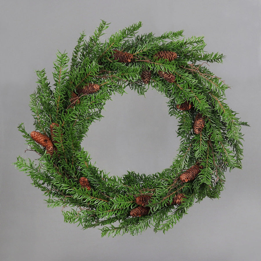 Mesterséges nobilis fenyőágakból készült, tobozokkal díszített ajtódísz koszorú.