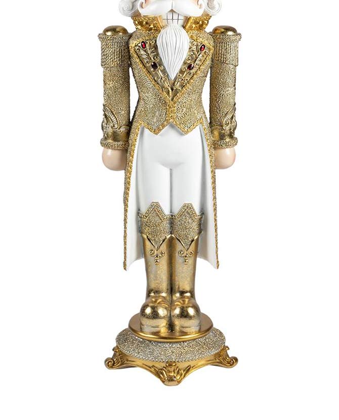 Fehér és aranyszínű, gazdagon díszlett karácsonyi diótörő király figura.