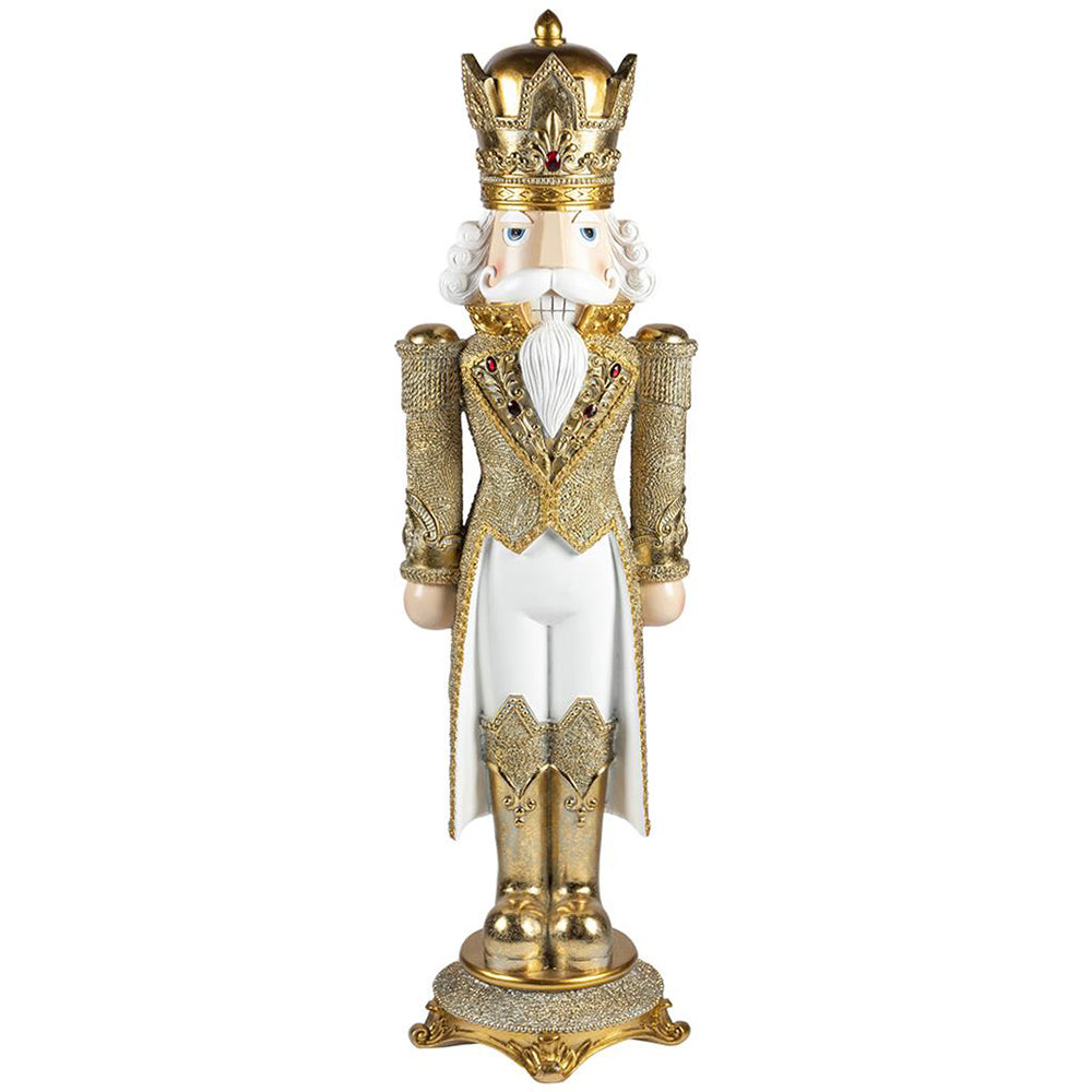 Fehér és aranyszínű, gazdagon díszlett karácsonyi diótörő király figura.