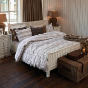 Klasszikus fehér ágy rusztikus enteriőrben párnákkal és takaróval