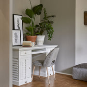 Fehér fa íróasztal növényekkel berendezett enteriőrben