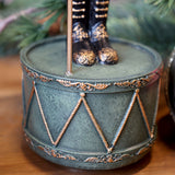 A NOÉL zenélő diótörő dobformájú zöld talapzata arany díszítéssel