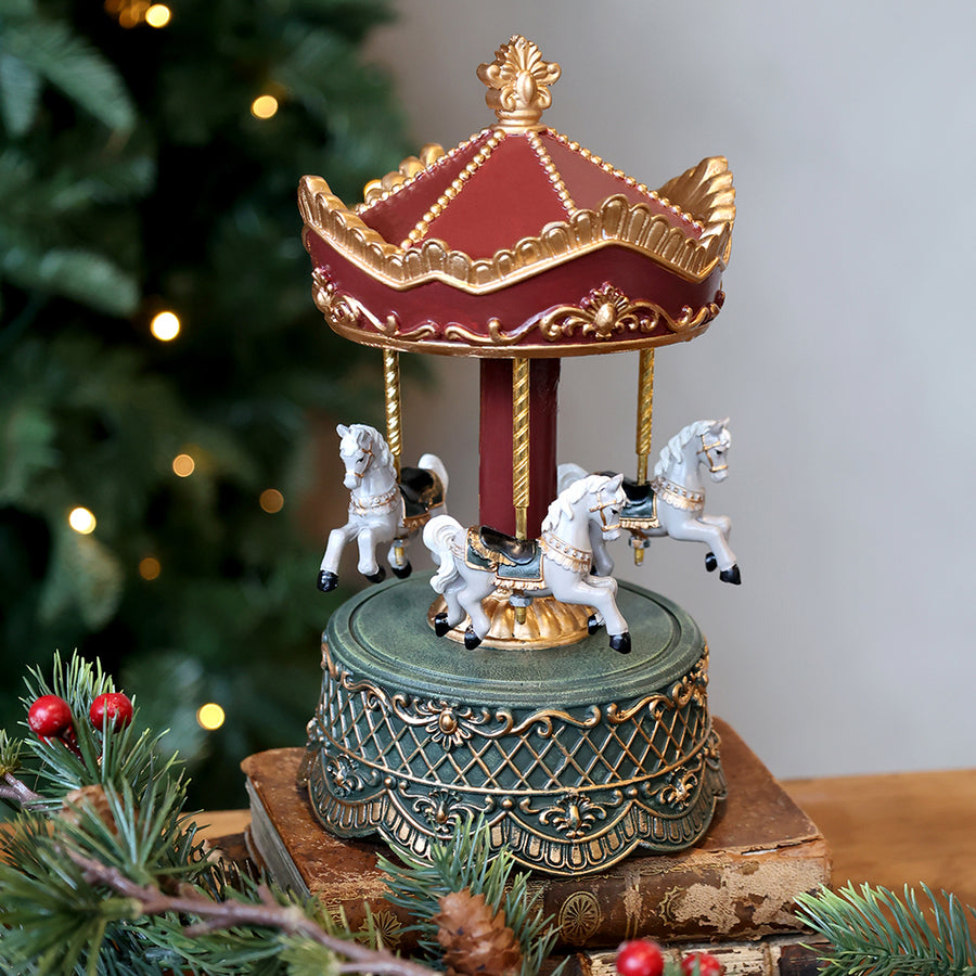 NOÉL zenélő bordó karácsonyi körhinta ünnepi enteriőrben, fenyőágak között