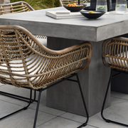 Fonott rattan kerti szék modern beton étkezőasztal mellett