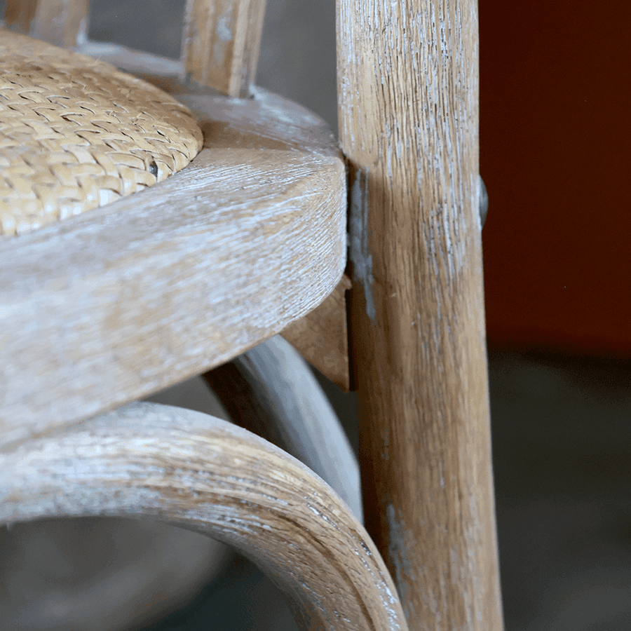 Közeli kép a fonott ülőfelület és fa ülőkeret találkozásáról, finom részletekkel.