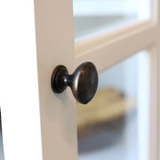 Fehér színű, 4 ajtós és 4 fiókos vitrines komódszekrény.