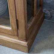 Natúr színű, 4 ajtós és 4 fiókos vitrines komódszekrény.