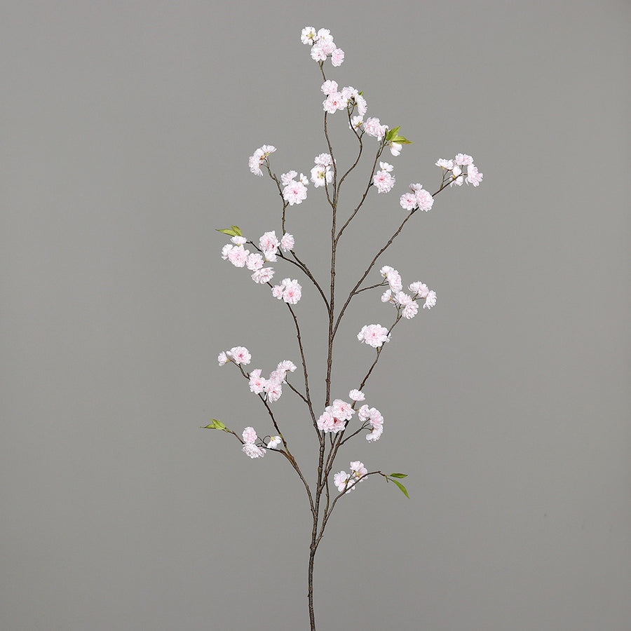 Virágzó mű cseresznyefa ág, halvány rózsaszín színű nyílt és bimbós virágokkal.