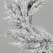 Karácsonyi havas mű fenyő koszorú tobozokkal közelről