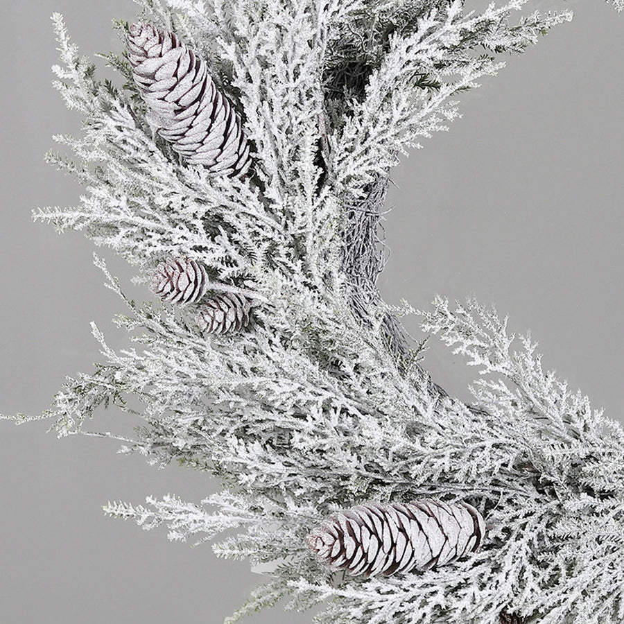 Karácsonyi havas mű fenyő koszorú tobozokkal közelről