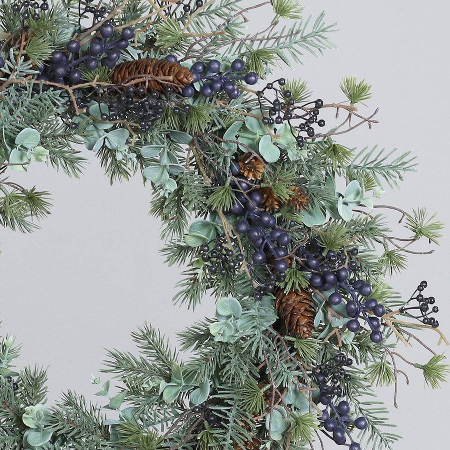 Fenyő mix koszorú közelebbi nézetben, eukaliptusz levelekkel és tobozokkal.