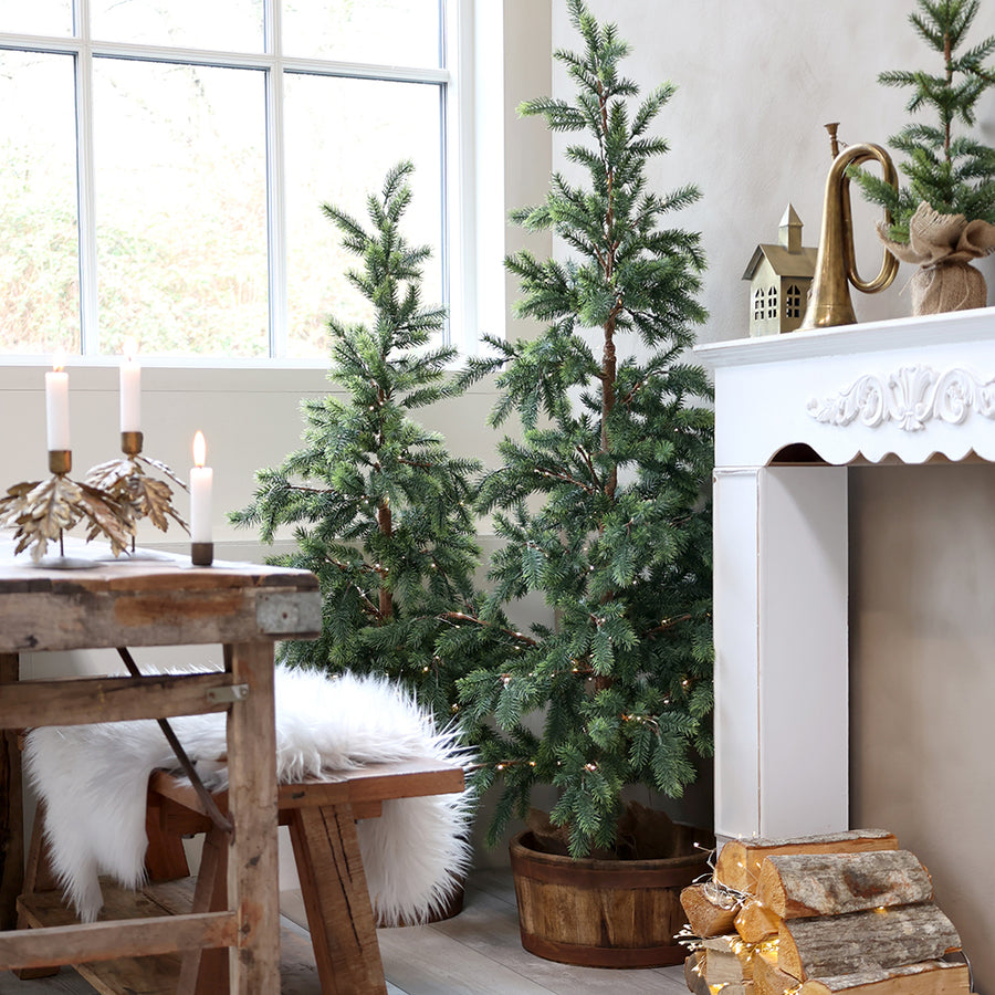 150 cm-es Pine LED műfenyő természetes nappali környezetben, kandalló mellett