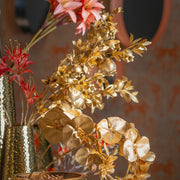 Glamour stílusú arany dekorációs ág gránátalmákkal, ünnepi enteriőrben.