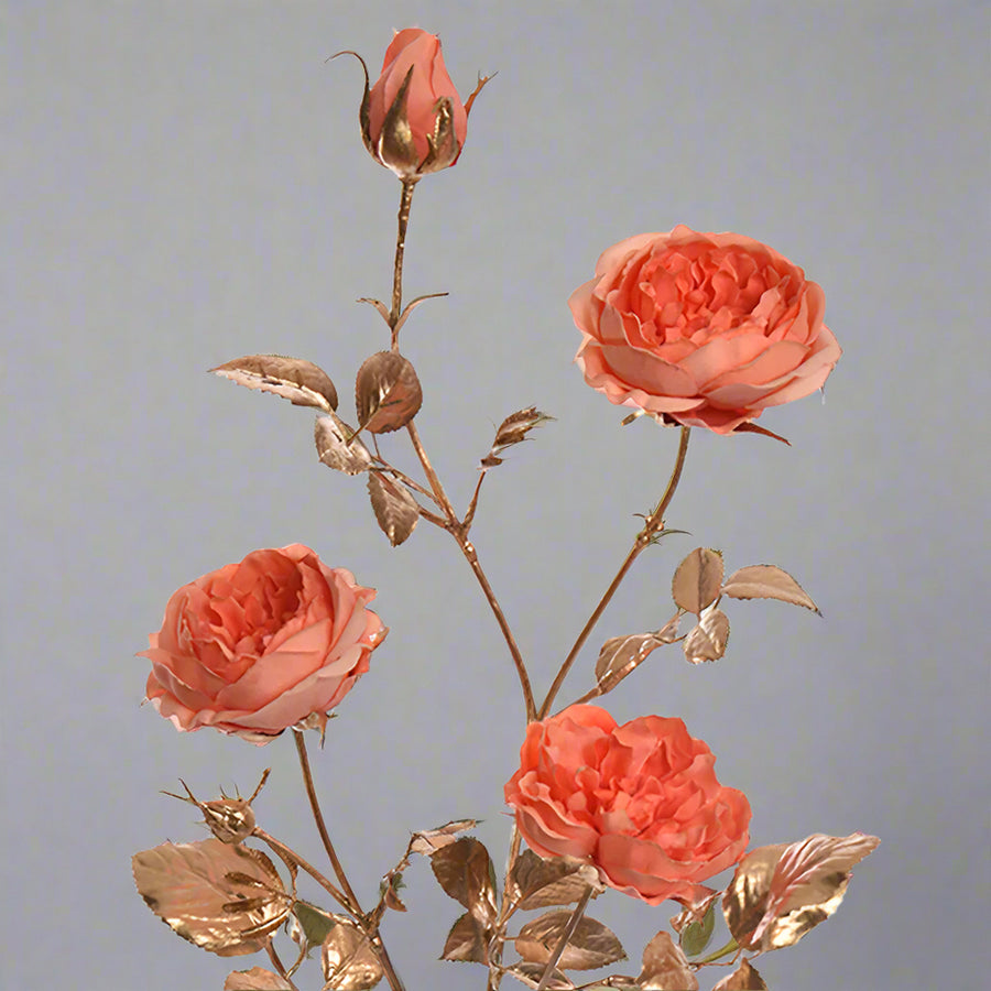 Elegáns, csillogó mű rózsaág közelről, fényes arany levelekkel.