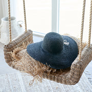 Rattan hinta párnával és kalappal enteriőrben