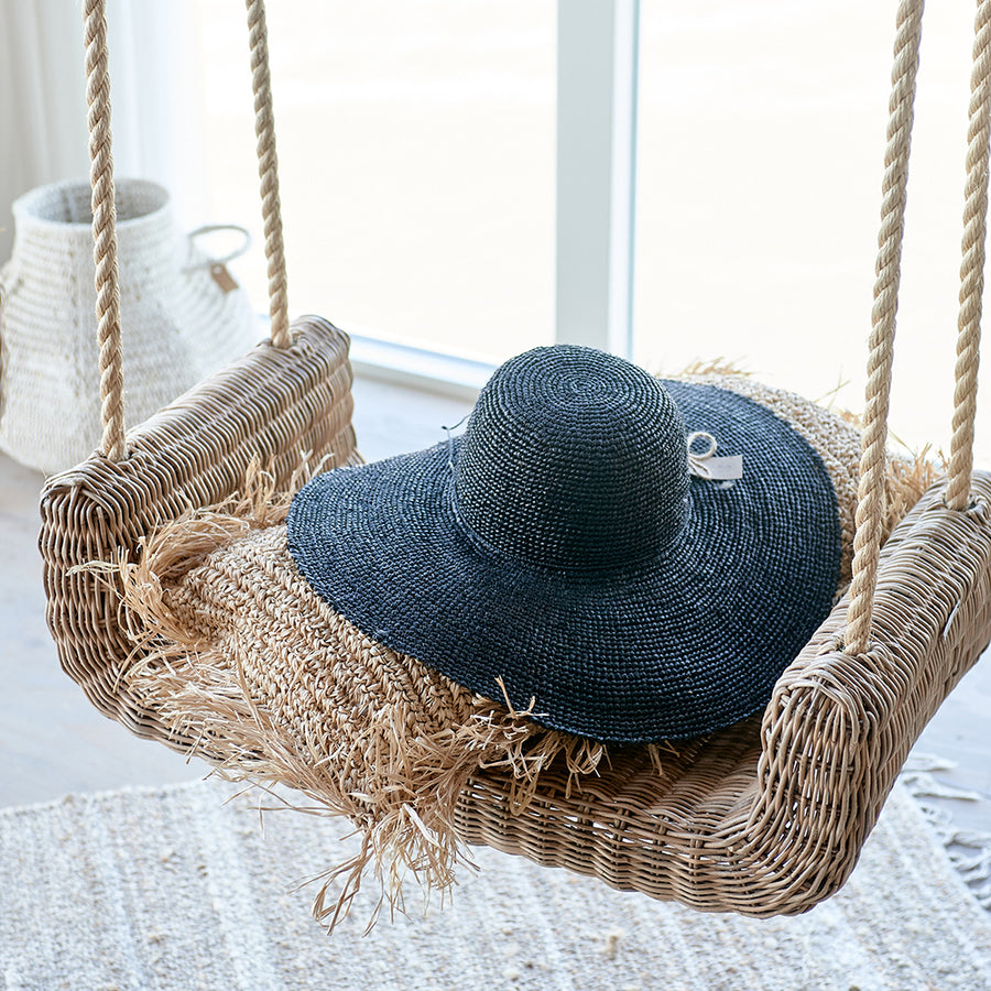 Rattan hinta párnával és kalappal enteriőrben