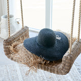 Rattan hinta párnával és kalappal enteriőrben