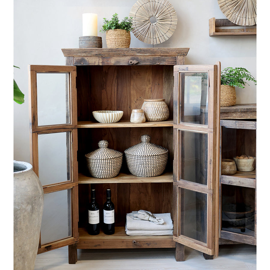 Nyitott ajtós vitrines szekrény dísztárgyakkal.