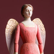 SACRED angyal figura arcközeli – rózsaszín ruha és arany tónusú fém szárny részlet
