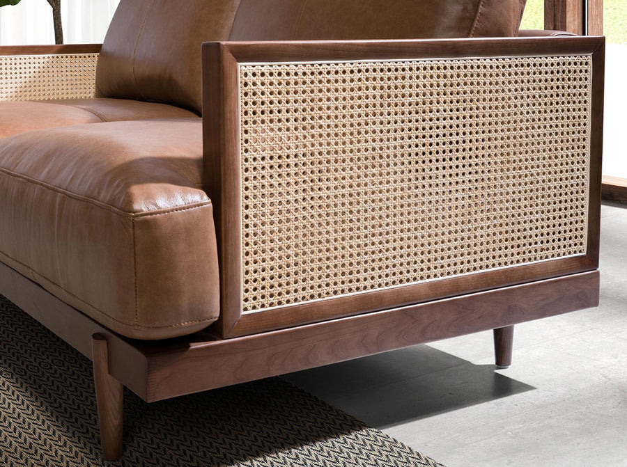 Barna színű marhabőrrel kárpitozott, rattanbetétes, 2 személyes design kanapé.