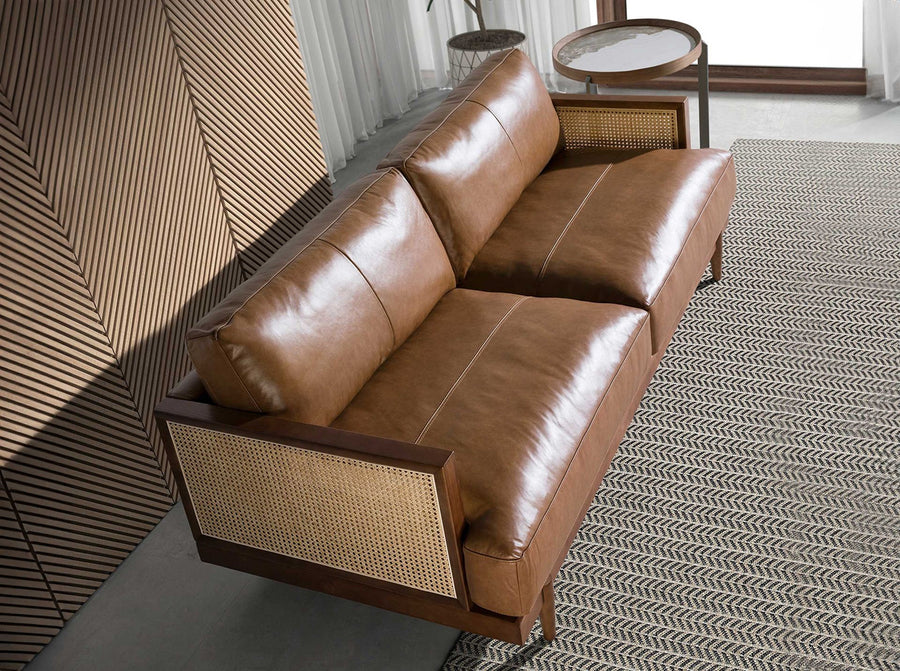 Barna színű marhabőrrel kárpitozott, rattanbetétes, 3 személyes design kanapé.