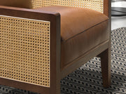 Konyakbarna színű marhabőrrel kárpitozott, rattanbetétes design fotel.