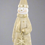 Arany hóember figura közelről, részletgazdag köpenymintával és hópehelydísszel a kezében.