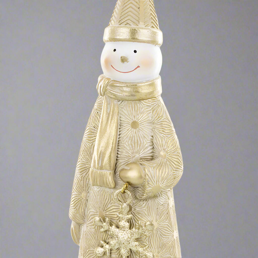 Arany hóember figura közelről, részletgazdag köpenymintával és hópehelydísszel a kezében.