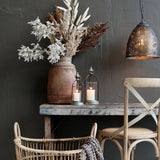 Sorghum mokkaszínű magvas mű ág rusztikus asztalon, lámpás és szék mellett