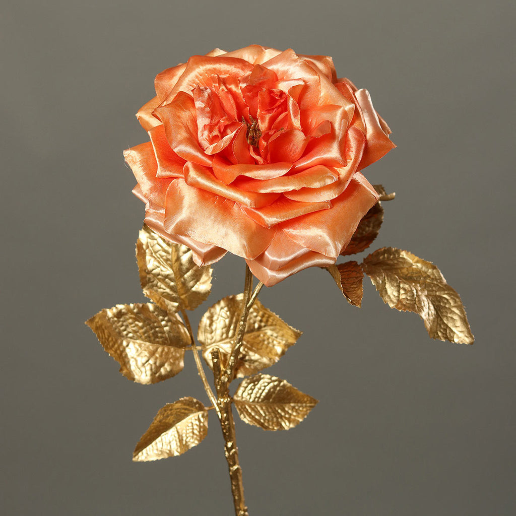 Fényes aranyszínű szárú és levelű, lazac színárnyalatú szatén rózsa művirág .