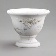 Rusztikus hatású, talpas cement kaspó kopottas, törtfehér felülettel, klasszikus formában.