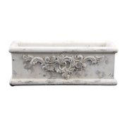 Antikolt krémszínű cement ültetőláda növényi díszítéssel, szemből fotózva