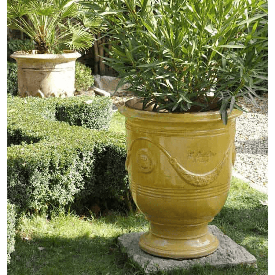 Sárga anduze kaspó leanderrel kertben.