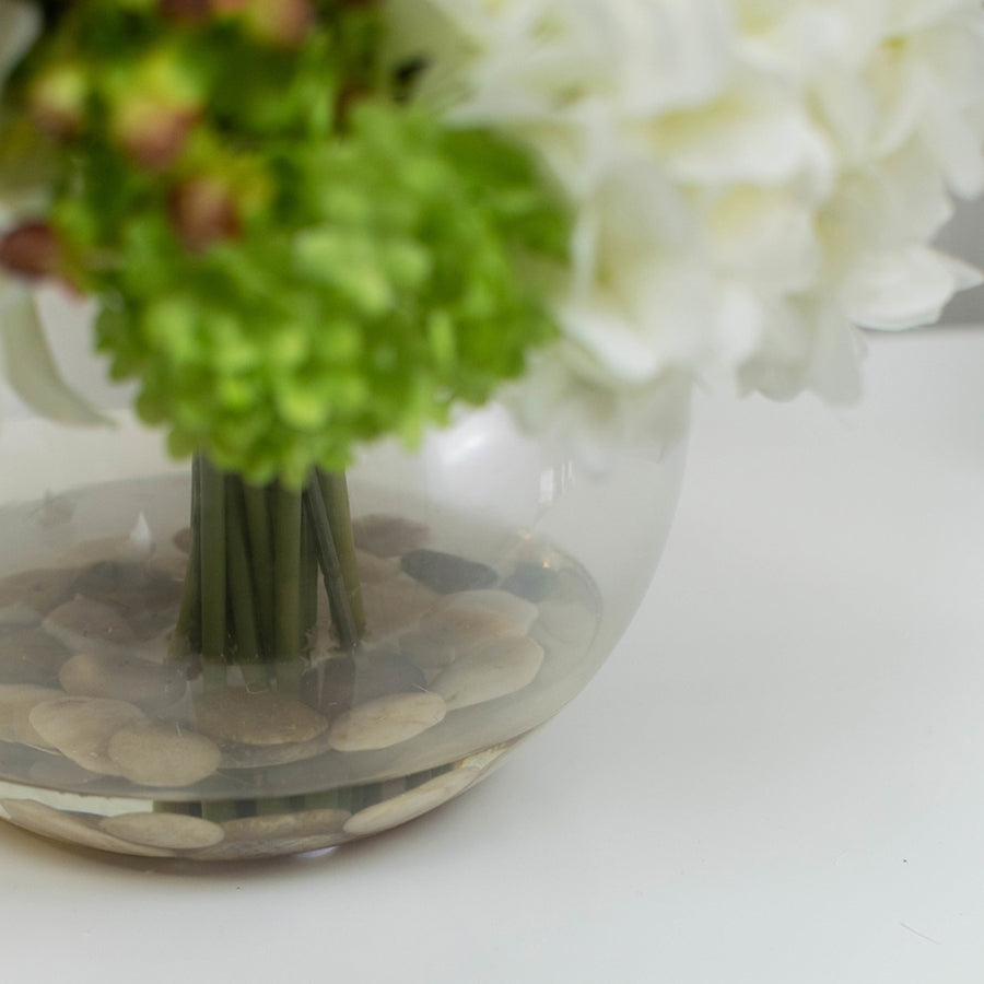 Mű hortenziákból és bazsarózsákból készült nagy virágcsokor, áttetsző üvegvázában.