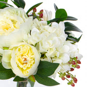 Mű hortenziákból és bazsarózsákból készült nagy virágcsokor, áttetsző üvegvázában.