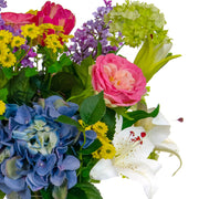 Vegyes művirágokból készült nagy virágcsokor, áttetsző üvegvázában.