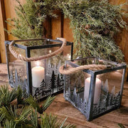 Vidéki rusztikus stílusú, antikolt szürke színű 2 darabos karácsonyi sziluettes fém lámpásszett fenyőkoszorú előtt antikolt fa deszkaasztalon 