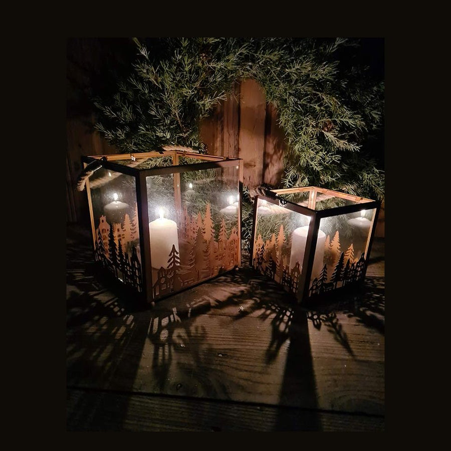 Vidéki rusztikus stílusú, antikolt rozsdás színű 2 darabos karácsonyi sziluettes fém lámpásszett fenyőkoszorú előtt antik faasztalon