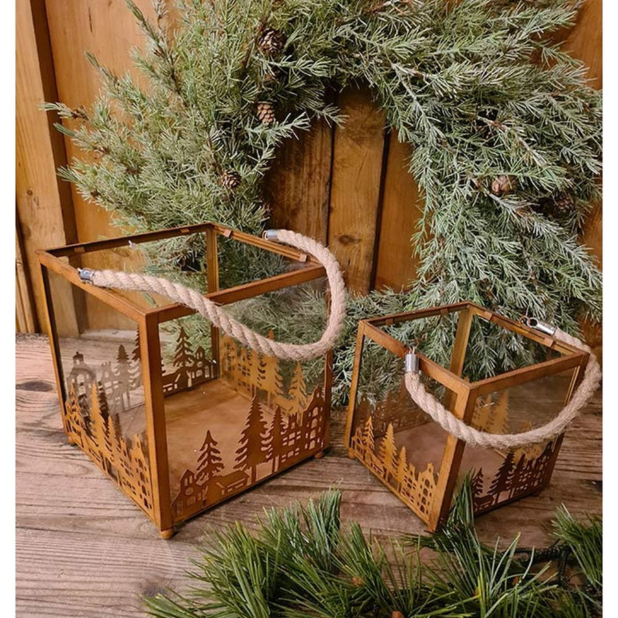 Vidéki rusztikus stílusú, antikolt rozsdás színű 2 darabos karácsonyi sziluettes fém lámpásszett fenyőkoszorú előtt antik faasztalon