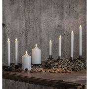Többféle méretű led gyertyák, rusztikus fa asztalon, antik, szürke színű fal előtt 