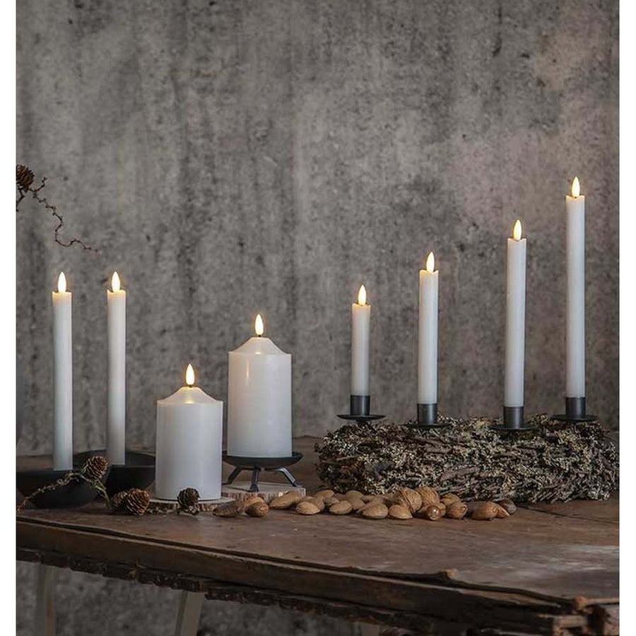 Többféle méretű led gyertyák, rusztikus fa asztalon, antik, szürke színű fal előtt 